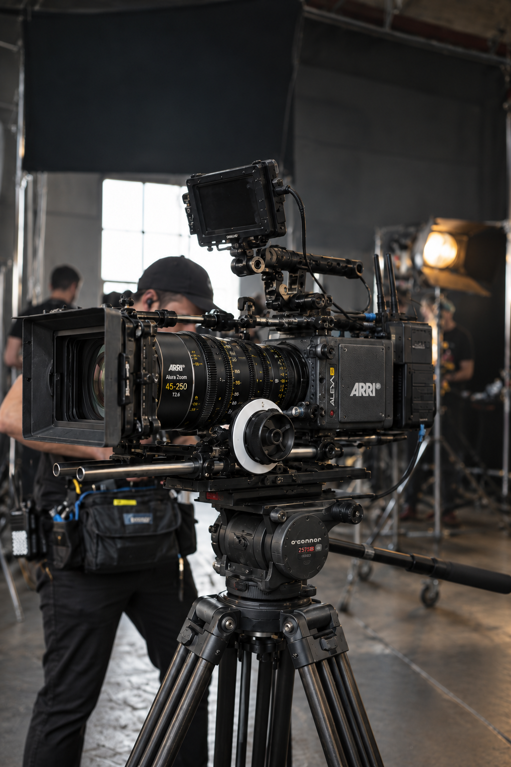 ARRI cinema camera with a zoom lens on a fluid-head tripod in a working studio